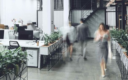 Modernes Büro mit Pflanzen und Mitarbeitern im Hintergrund